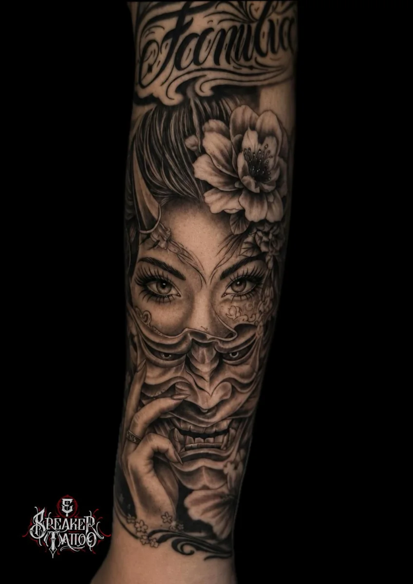 Frauengesicht das in eine Hannya-Maske übergeht, Kirschblüte im Haar, auf dem Unterarm in Black and Grey